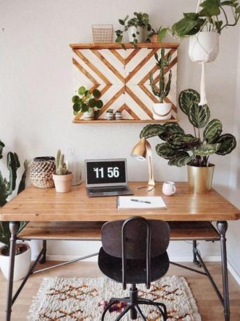 Úžasná domácí kancelář v boho stylu s retro dřevěným stolem, kobercem boho.