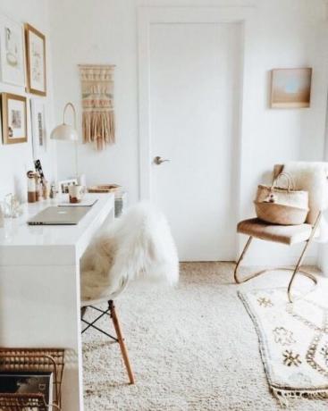 Domácí kancelář ve světlých odstínech, bílý leštěný stůl, makramé, malý koberec, proutěné předměty